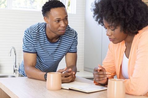 African american couple reviewing finances, planning at modern minimalist kitchen counter
