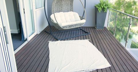 Cozy balcony with hanging chair and blanket setup for relaxation