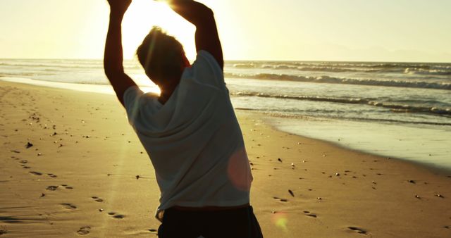 Man stretching on beach during sunset, creating silhouette against ocean background. Perfect for themes of fitness, mindfulness, relaxation, nature, health, and active lifestyle content. Ideal for promotions of wellness retreats, travel blogs, exercise routines, and inspirational posts about embracing the outdoors and staying fit.