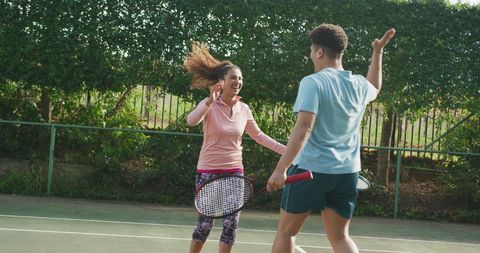 Energetic Couple Enjoying Tennis Match on Sunny Day