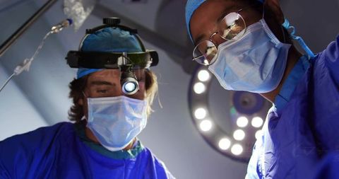 Surgeons performing delicate operation in modern operating room with surgical loupes