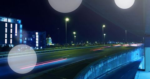 Nighttime urban overpass with long-exposure light trails and neon blue architecture