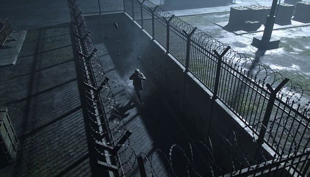 Night guard patrolling narrow perimeter trench under razor wire fence