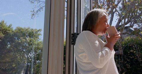 Senior Woman Enjoying Coffee by Sunny Window Outdoors