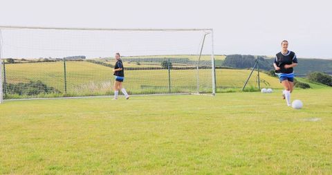 Teenage Soccer Players Practicing Near Goal on Grassy Field