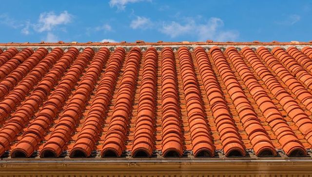 Repeating terracotta barrel roof tiles creating warm geometric pattern under blue sky