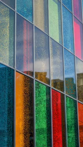 Panning up vibrant textured glass facade with diagonal mullions and reflective panels
