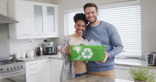 Image of happy diverse couple embracing and holding recycling bin with plastic bottles. Relationship, living together, recycling and eco awareness concept digitally generated image.
