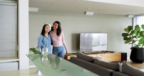 Hispanic Female Friends Hugging in Modern Living Room