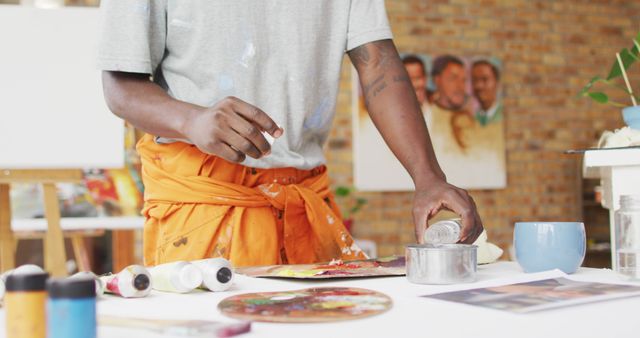 Midsection of african american male painter mixing paint in artist studio. art, creative and leisure time concept.