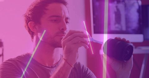 Camera technician repairing lens in neon-lit studio
