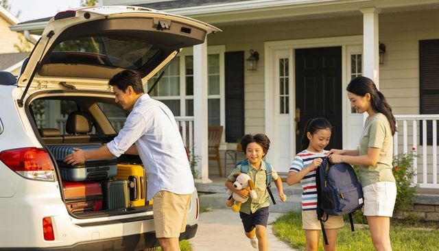 Family packing suv trunk in suburban driveway preparing for weekend road trip