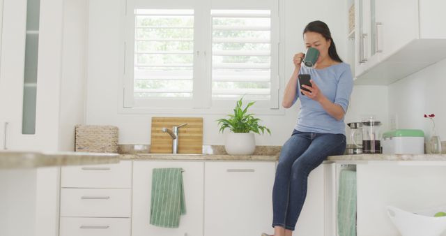 Woman Enjoying Coffee in Modern Kitchen While Checking Phone - Download Free Stock Images Pikwizard.com