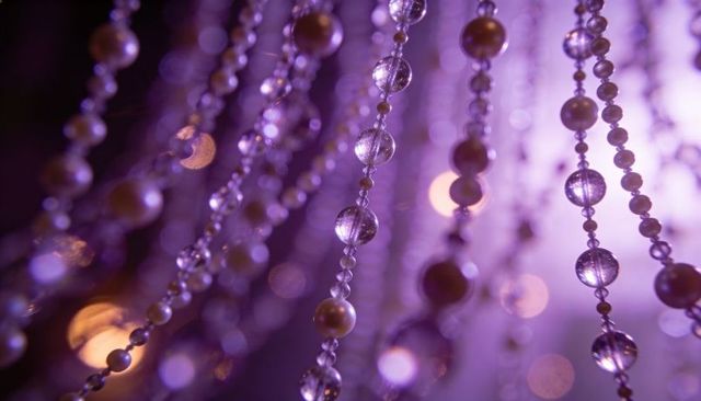 Glittering purple bead curtain catching light with pearls glass beads and bokeh background