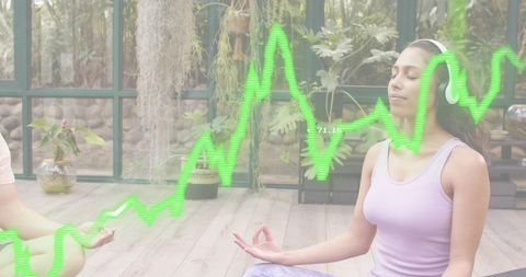 Woman meditating with headphones in sunlit plant studio with digital wave overlay