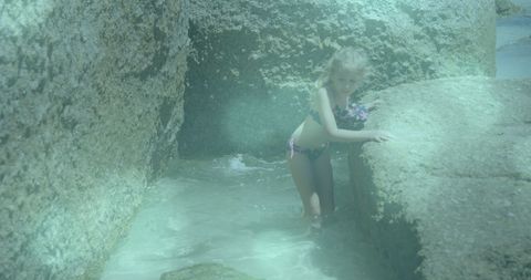 Child exploring rocky shores in sunny beach setting