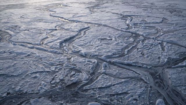 Fracturing polar pack ice forming winding melt channels and jagged sea-ice floes overhead