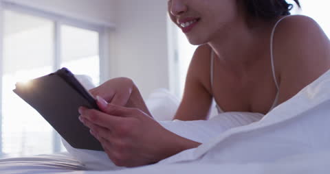 Woman Relaxing in Bed Using Tablet
