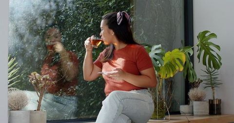 Contemplative Woman Enjoying Tea by Window in Paused Harmony
