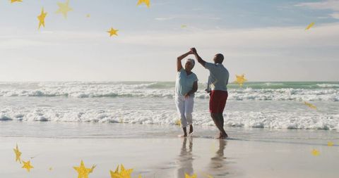 Dancing mature couple twirling on sunlit beach with wet reflections and golden stars