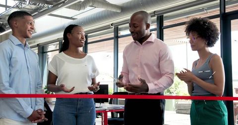 Leading ribbon-cutting celebration in modern open-plan office with collaborative team