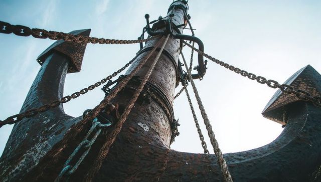 Towering rusted anchor with heavy chains and ropes closeup, weathered maritime texture