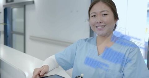 Smiling Korean Nurse Using Tablet at Hospital Reception for Patient Care and EHR Access
