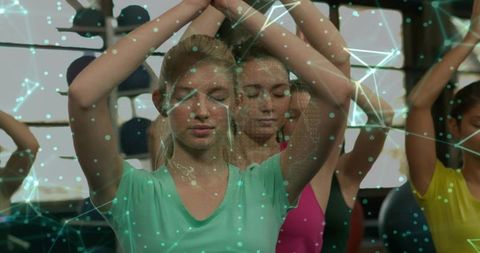 Women Practicing Mindful Yoga and Meditation with Digital Network Overlay in Fitness Studio