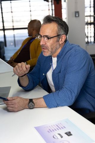 Middle-aged professional discussing strategy with diverse coworkers in bright office