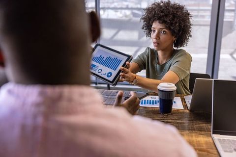 Business Professionals Discuss Analytics with Tablet Presentation