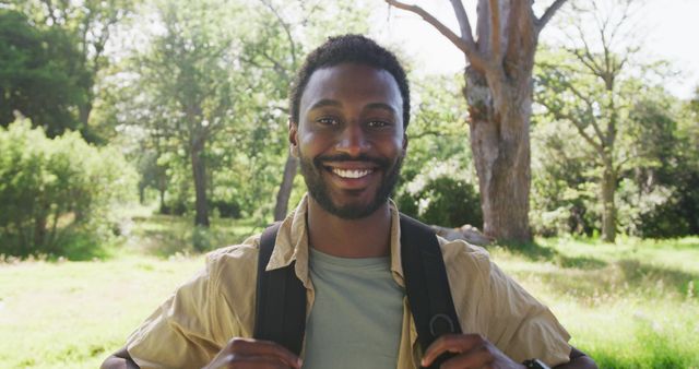 Man smiles while enjoying a hike in a forest. Great for themes about nature, outdoor activities, happiness, and travel. Images like this are wonderful for advertisements promoting adventure tours, trekking gear, travel blogs, or nature-themed wellness programs.