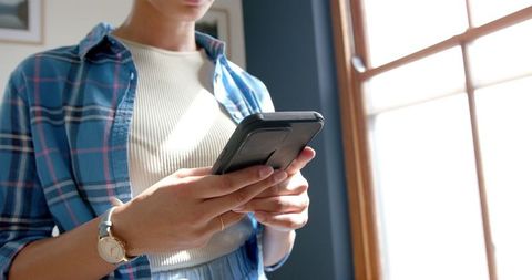 Teenage Girl Using Smartphone in Bright Sunny Room