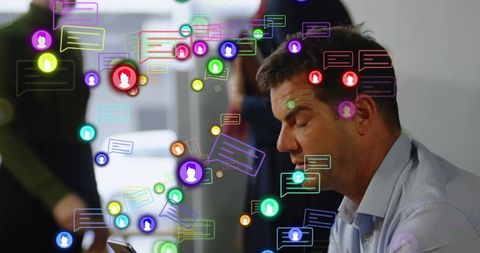 Businessman checking smartphone amid holographic chat icons showing team collaboration