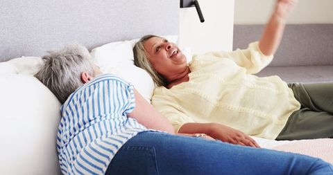 Happy Senior Lesbian Couple Laughing on Bed
