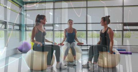 Three women exercising with stability balls and dumbbells in modern gym