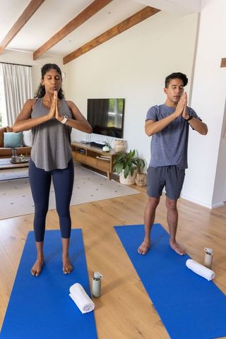 Couple practicing yoga at home on blue mats for meditation, mindfulness and balance