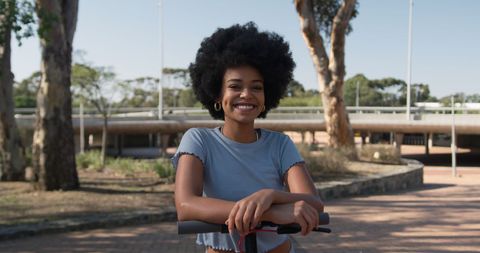 Portrait of Smiling Woman with Scooter in Sunny Park