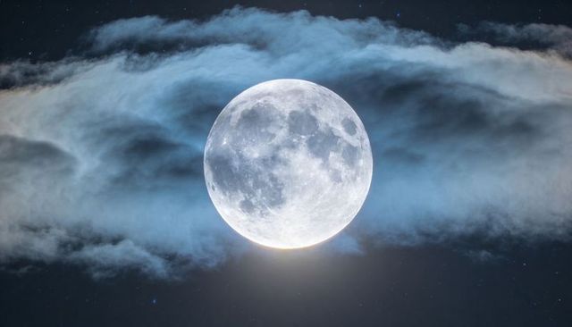 Glowing full moon revealing cratered surface with soft halo and drifting cloud band