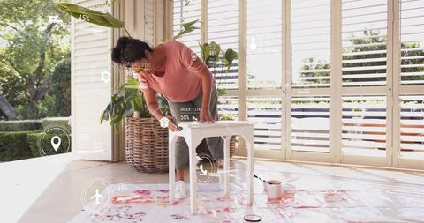 Woman sanding small table on sunroom porch with augmented reality diy overlays