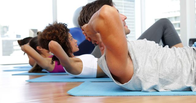 Group Fitness Class Doing Abdominal Crunches on Mats in Modern Gym - Download Free Stock Images Pikwizard.com