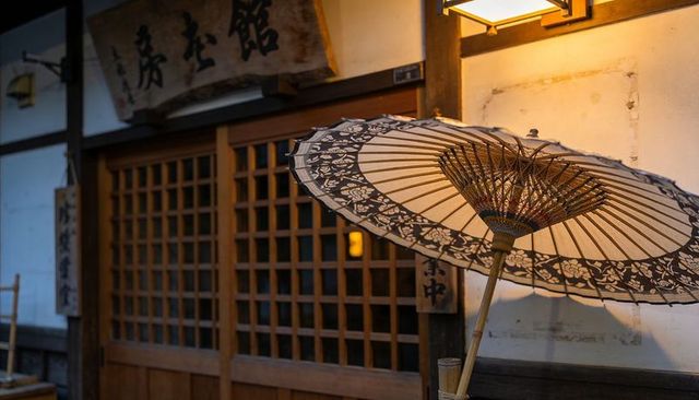 Wagasa umbrella leaning at traditional japanese teahouse entrance with warm lantern glow