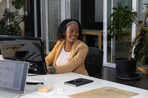 African american professional woman smiling while working at modern open-plan office desk