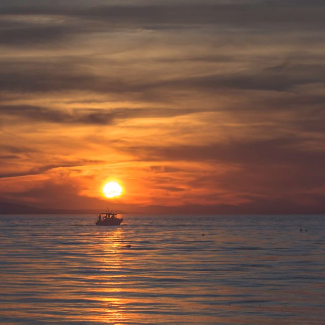 Fishing Boat Silhouetted Against Orange Sunset on Tranquil Sea - Download Free Stock Photos Pikwizard.com