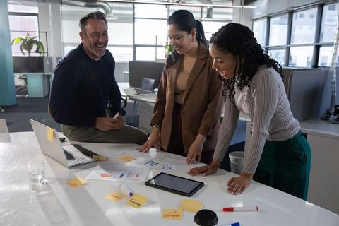 Multicultural team collaborating over charts and tablet during creative office meeting