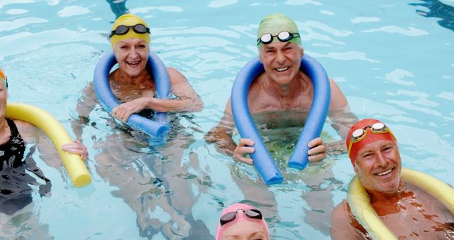 Elderly individuals participating in a water aerobics class in a swimming pool. They are all laughing and enjoying the activity, wearing swim caps and using colorful water noodles for support. Great for promoting healthy living, senior fitness programs, and active retirement communities.