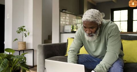 Senior Man Engaged with Laptop in Modern Living Room