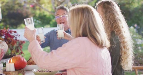 Multigenerational family toasting outdoors at backyard dinner with pumpkin and candlelight