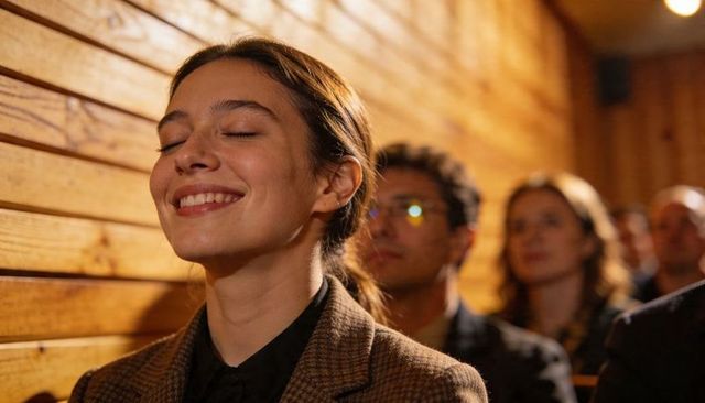 Smiling woman with eyes closed enjoying intimate moment during event in wood-paneled hall