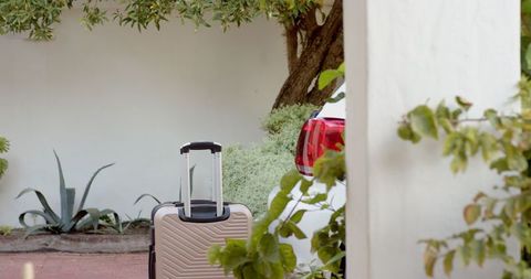 Stylish carry-on suitcase beside elegant stucco architecture