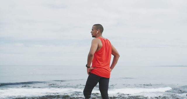 Male jogger taking a break from his workout to enjoy a scenic ocean view. Perfect for promoting fitness, healthy lifestyles, outdoor activities, coastal tourism, sportswear, and meditation or musings about personal goals and determination.